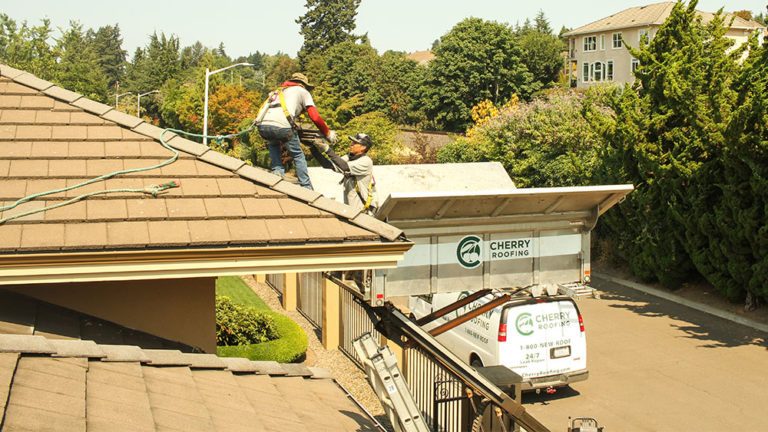 Cherry Roofing crew members removing debris from the roof of a home.