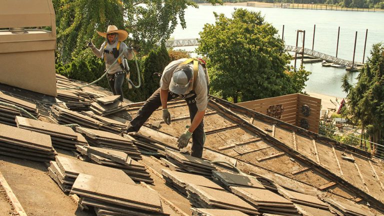 Two Cherry Roofing crew members hard at work on the roof of a home near the water.