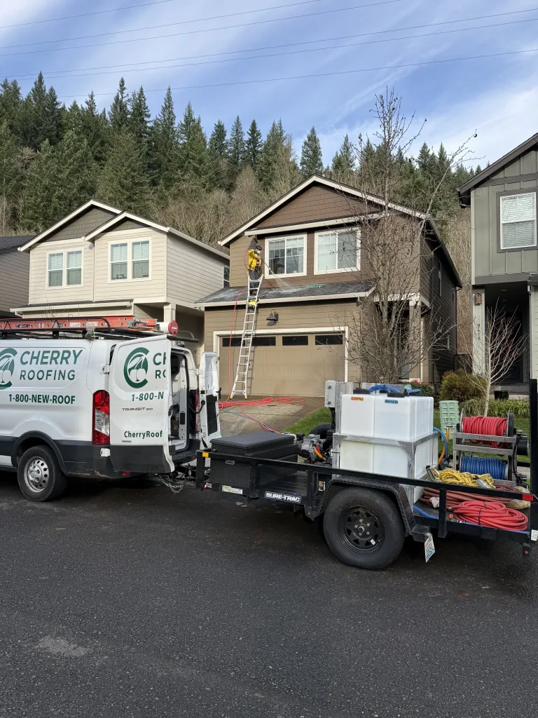 Cherry Roofing performing roof soft wash on two-story home in Vancouver WA using low-pressure cleaning system.