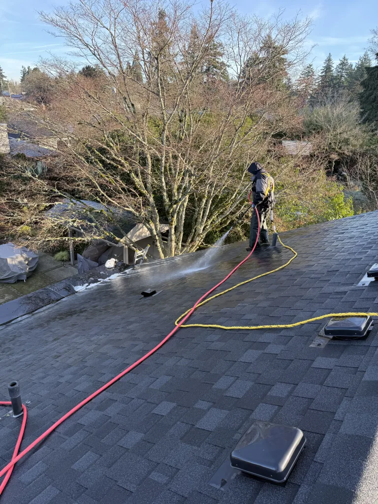 Cherry Roofing technician soft washing asphalt shingle roof in Vancouver WA with low-pressure cleaning method.