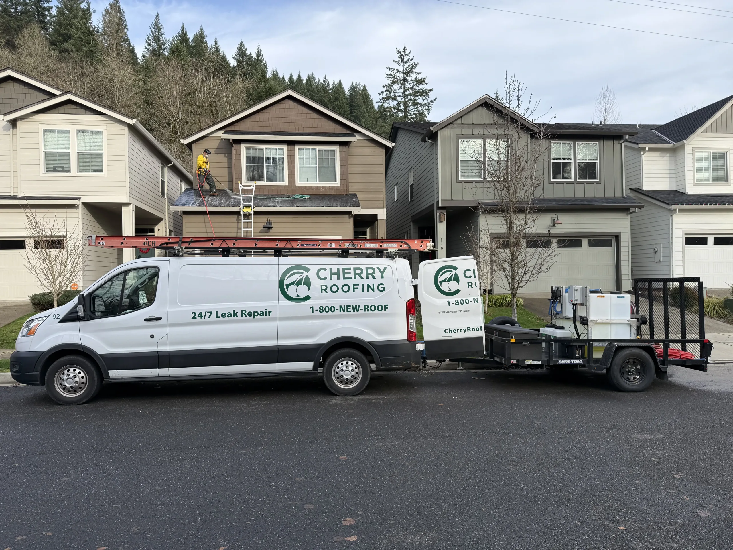 Cherry Roofing crew performing roof soft washing on residential home in Vancouver WA with service truck onsite.