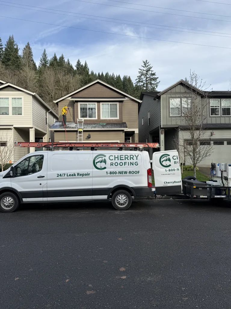 Cherry Roofing soft cleaning residential roof in Vancouver WA with company truck and equipment trailer onsite.